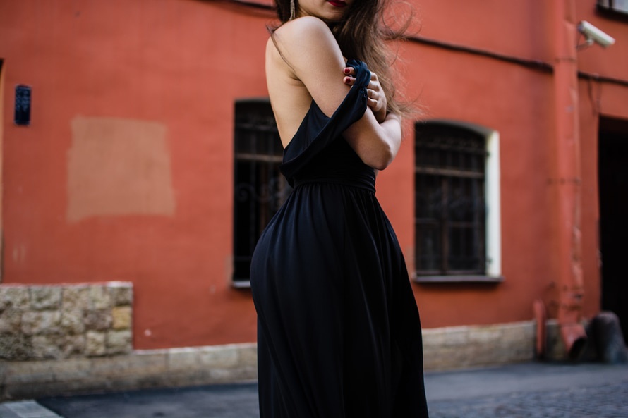 Cropped image of young woman in black dress with black strap falling of her shoulder.