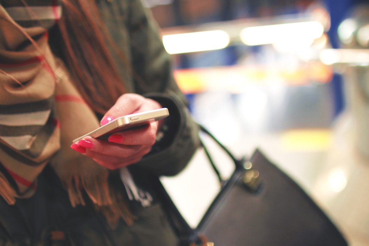 Young woman looks through phone on a regular day out.